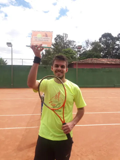 Bruno Cândido Barroso ergue a placa de campeão do Circuito AESEV de Tênis 2018 numa quadra de saibro